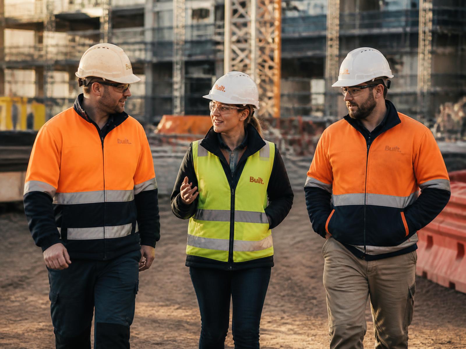 A woman project professional walking an active commercial site with two colleagues
